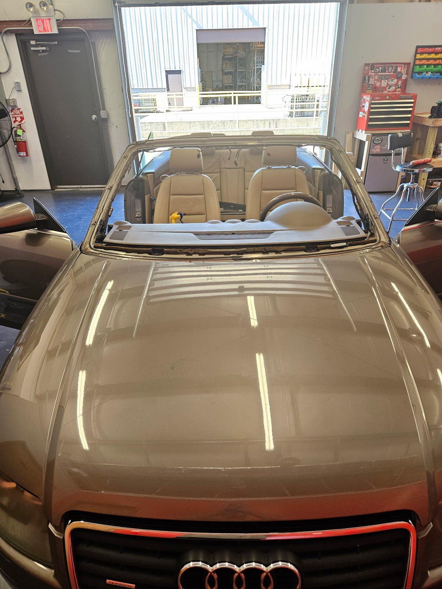 An Audi convertible is being worked on in a garage.