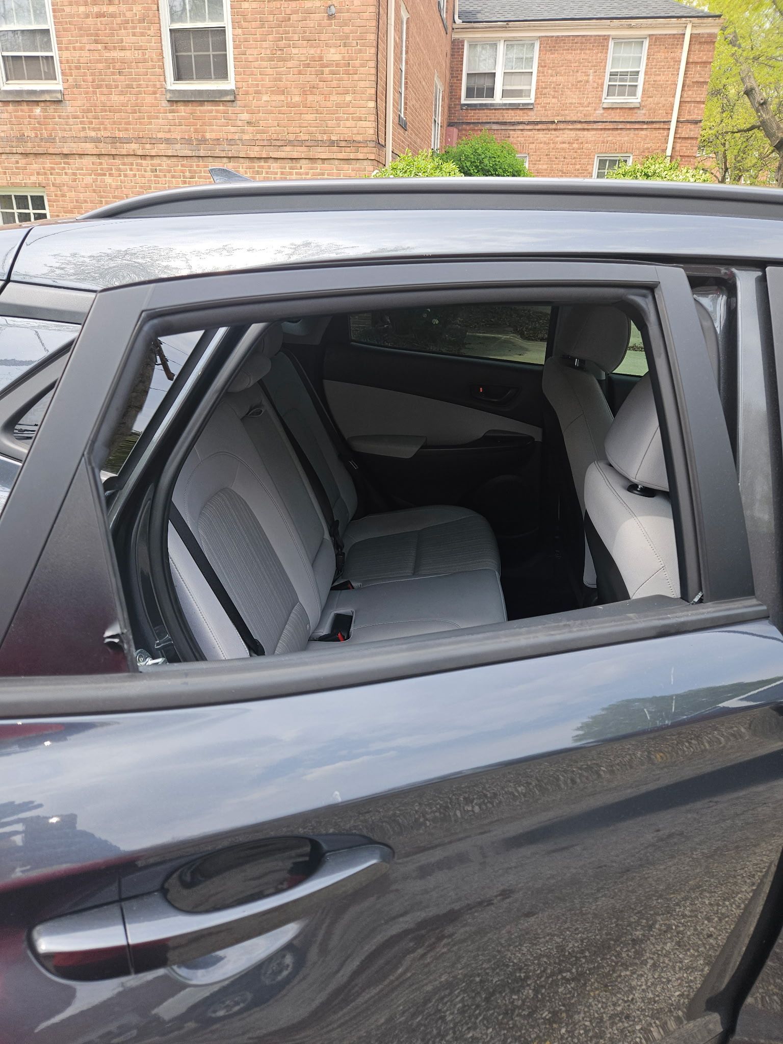 A black car is parked in front of a brick building.