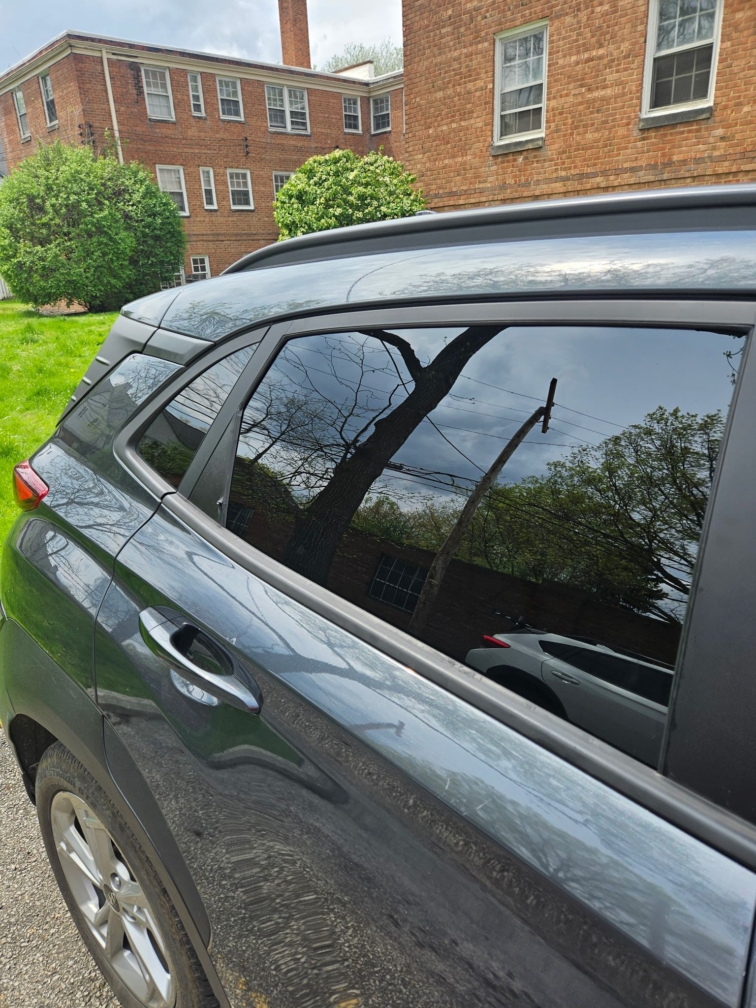 A black car with tinted windows is parked in front of a brick building.