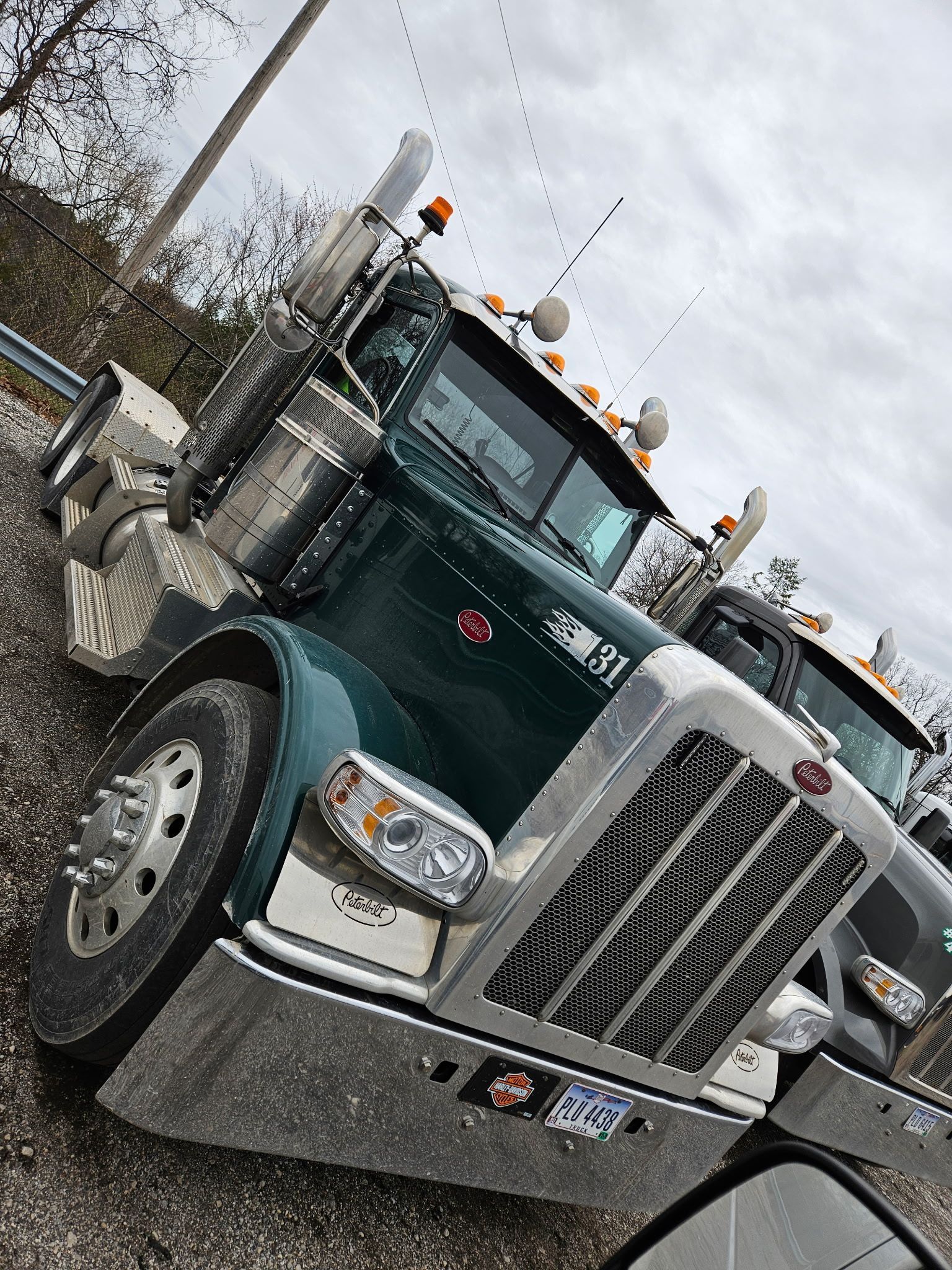 A green semi truck is parked on the side of the road.