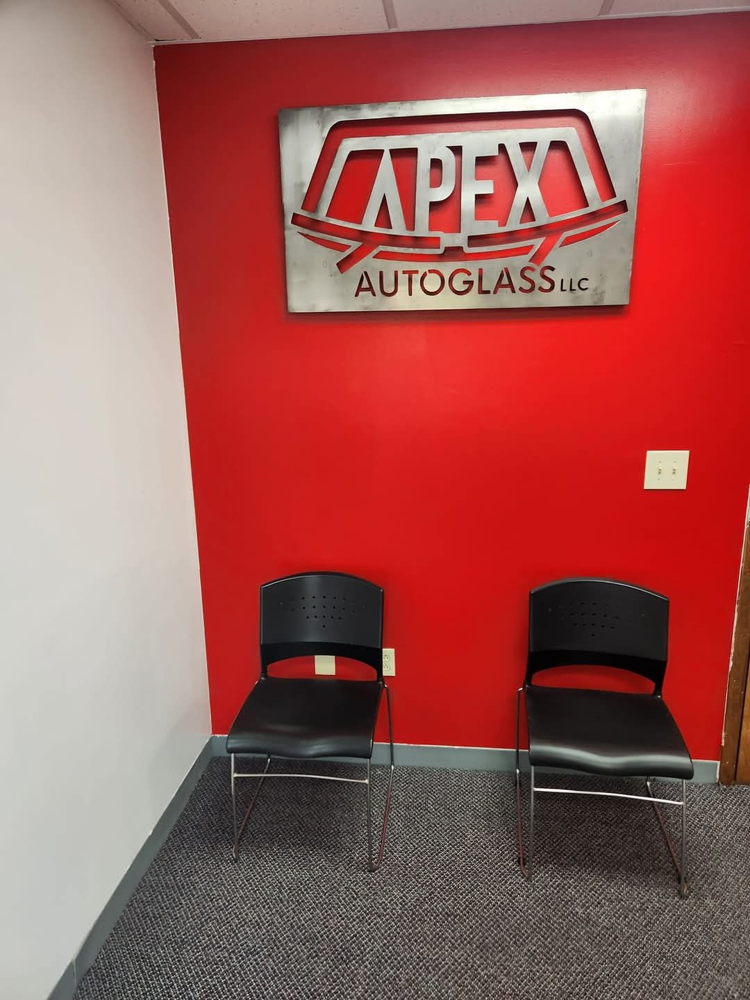 A room with two chairs and a sign that says apex auto glass.