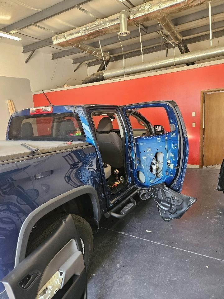 A blue truck is sitting in a garage with its doors open.