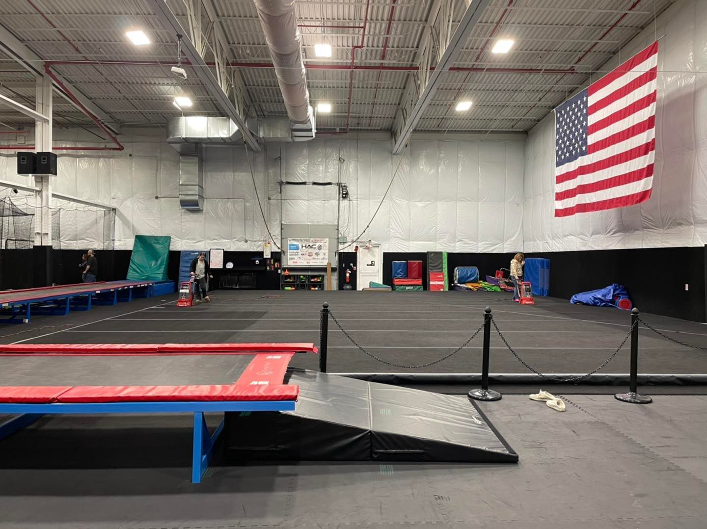 A large indoor gym with an american flag hanging from the ceiling.