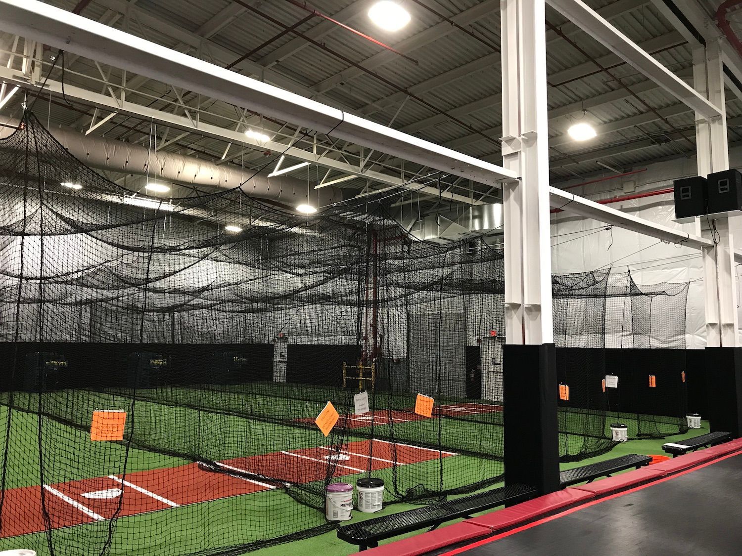 A large indoor baseball field with a lot of nets.