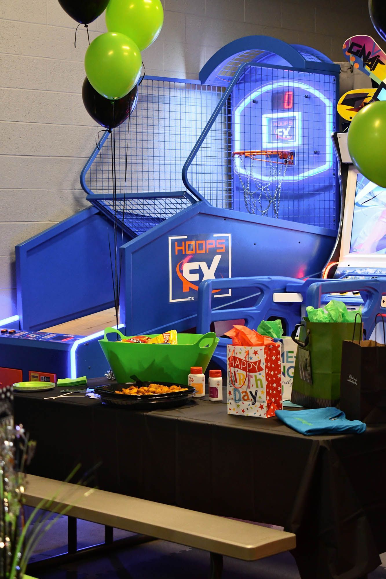 A table with balloons on it and a basketball hoop in the background.