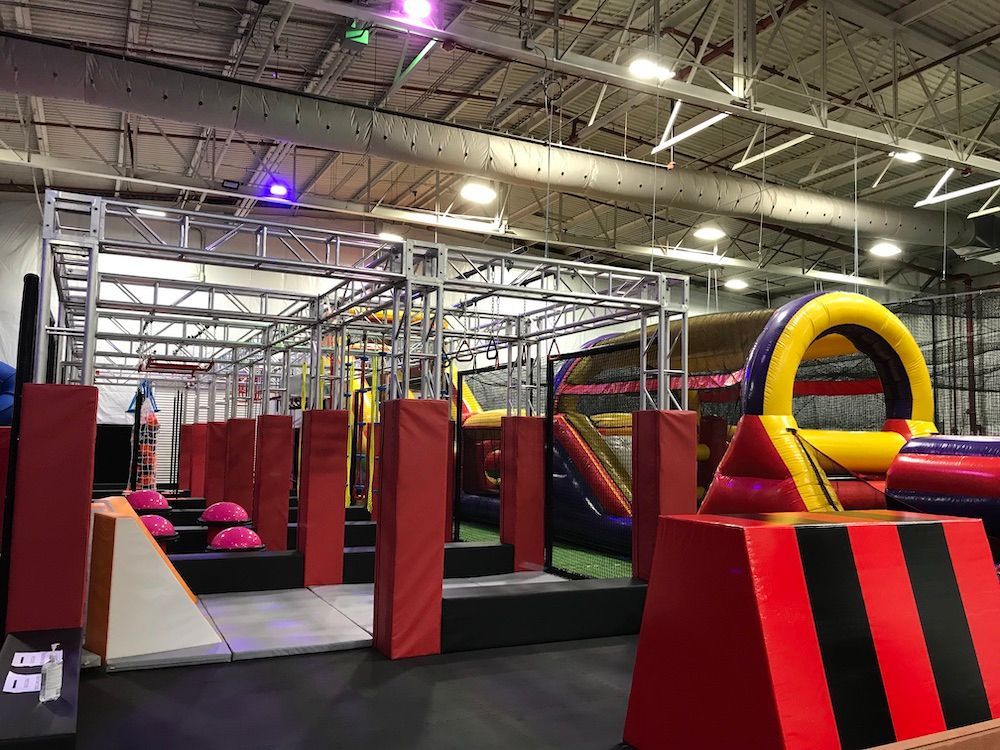 A large indoor playground with a ninja course and a bouncy house.