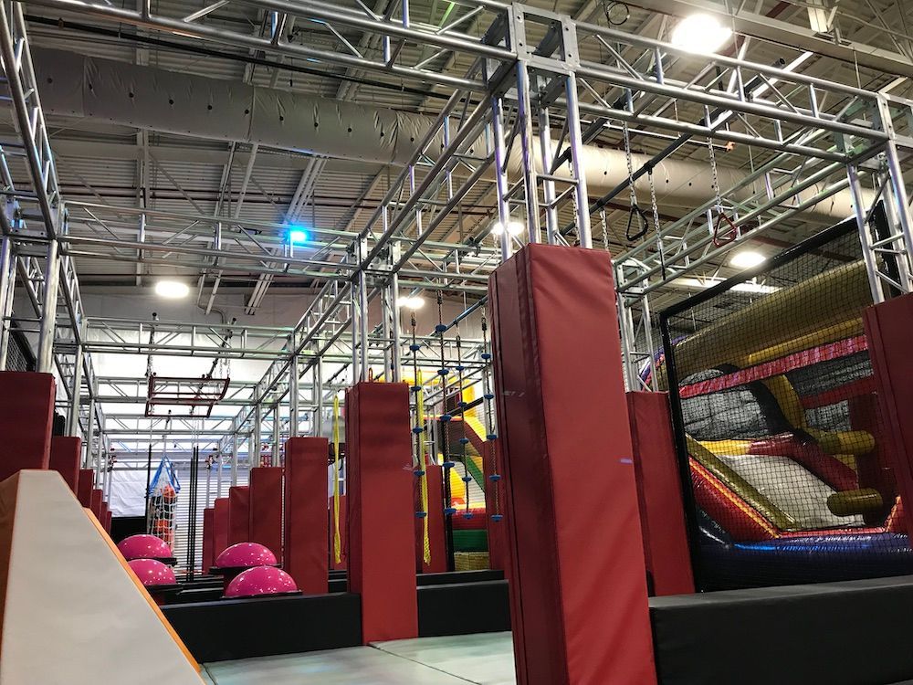 A large indoor playground with a slide and a ninja course.