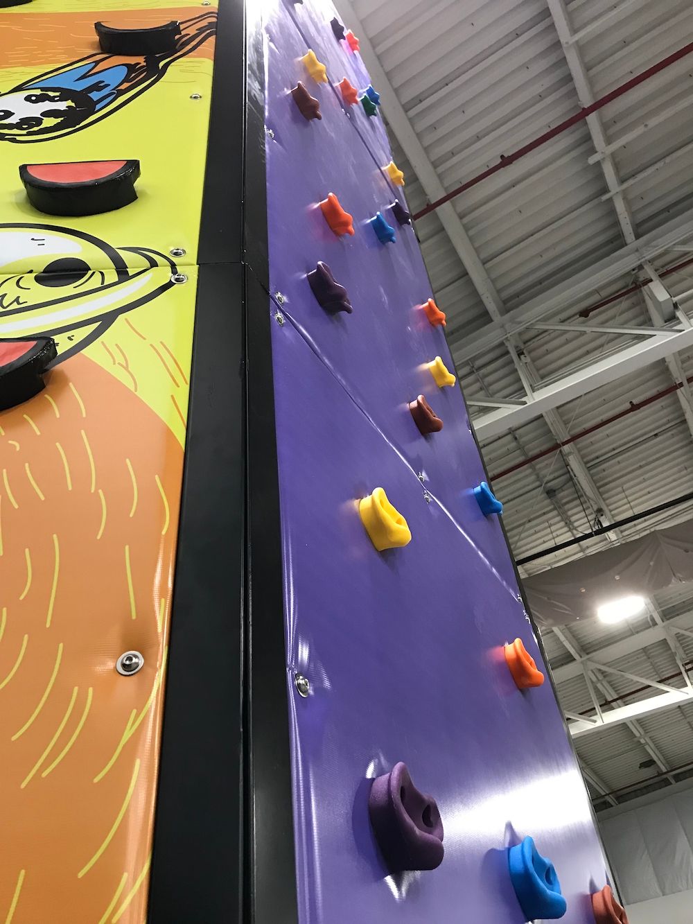 A purple climbing wall with many different colored holds