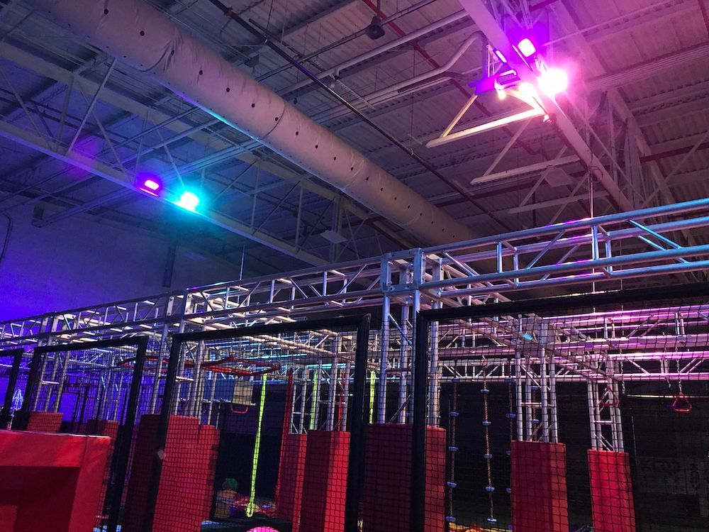 A ninja warrior course in a building with purple and blue lights