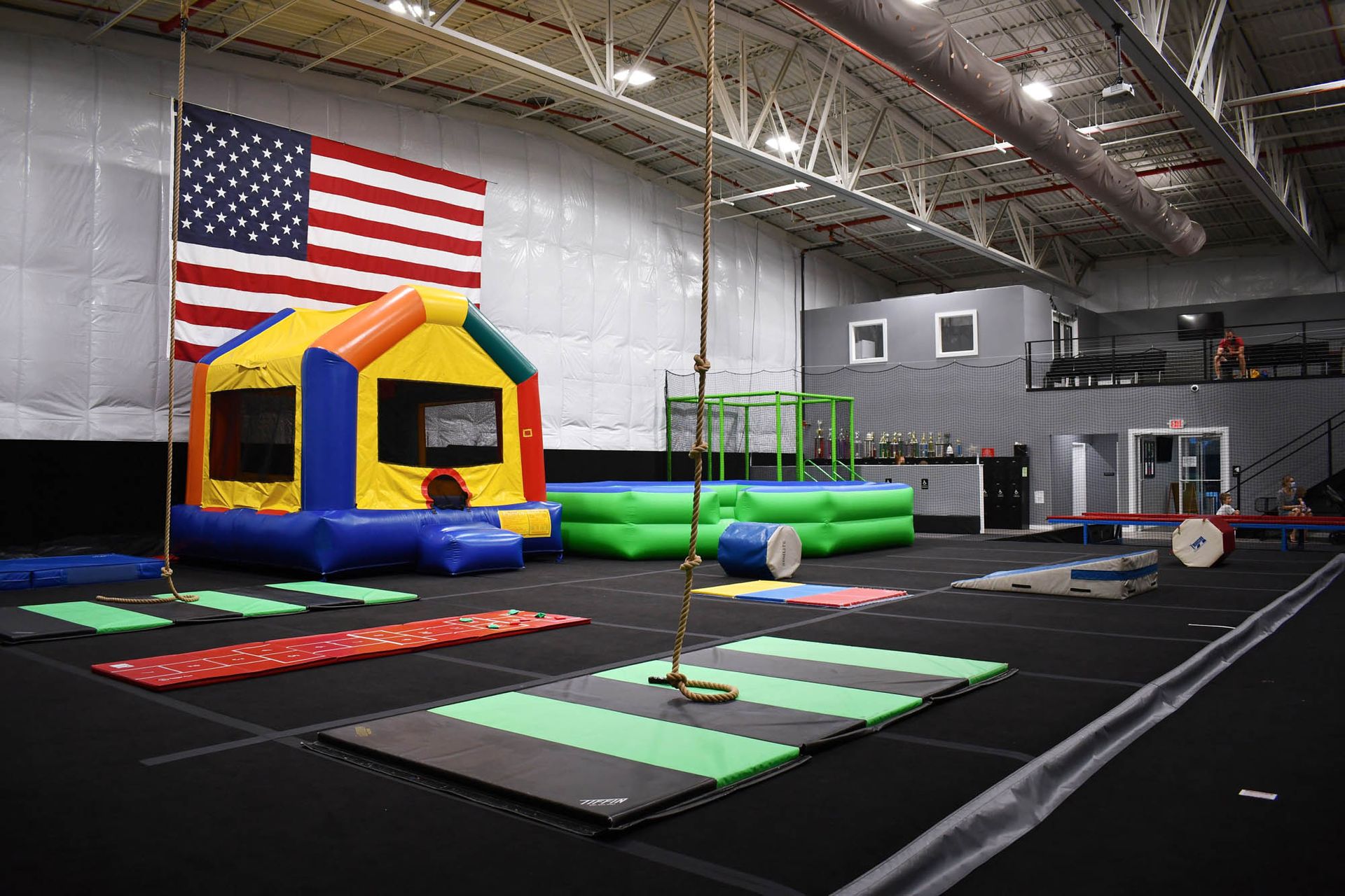 A large indoor gym with a bouncy house and an american flag.