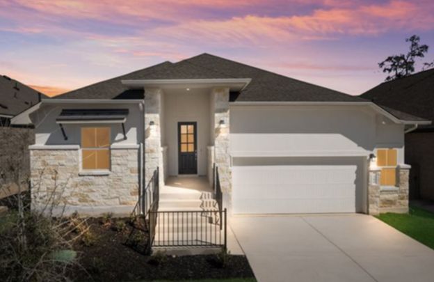 Modern single-story house with stone exterior, white garage, and front porch at sunset