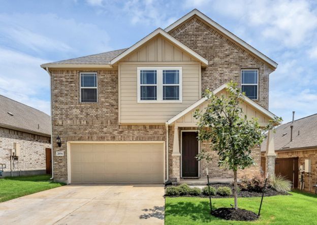 Two-story tan brick house with a two-car garage and small front lawn
