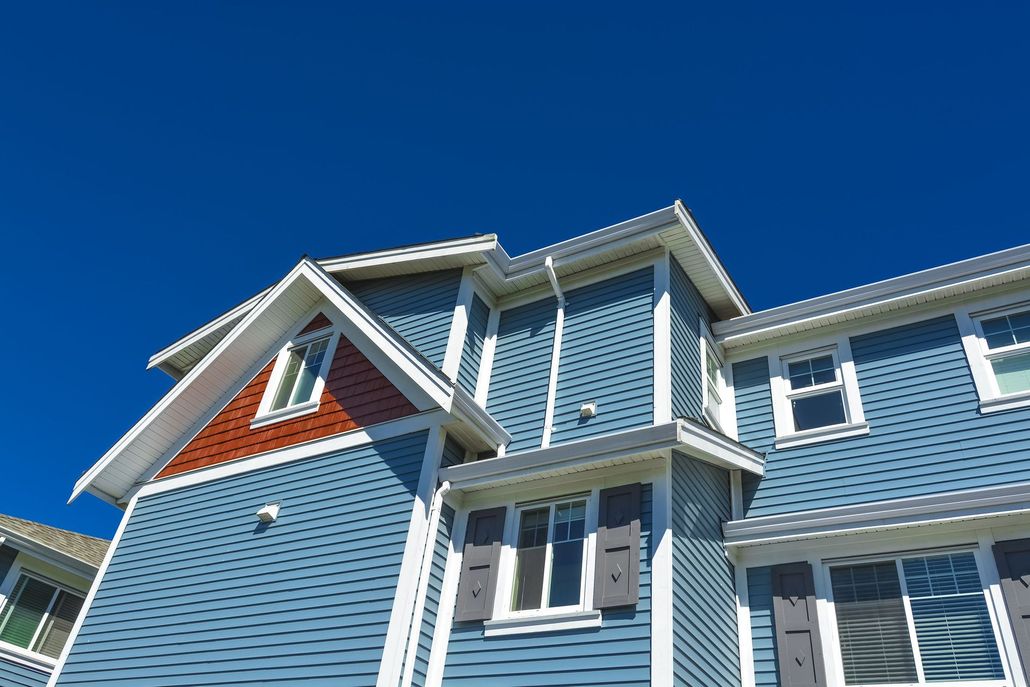 Blue house exterior with white trim and red accents under a clear sky