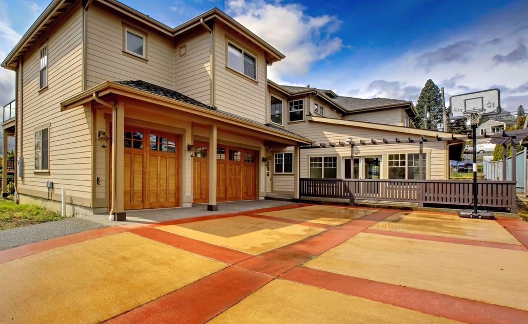Modern two-story townhouse with wood garage doors and a red-orange driveway in a residential complex