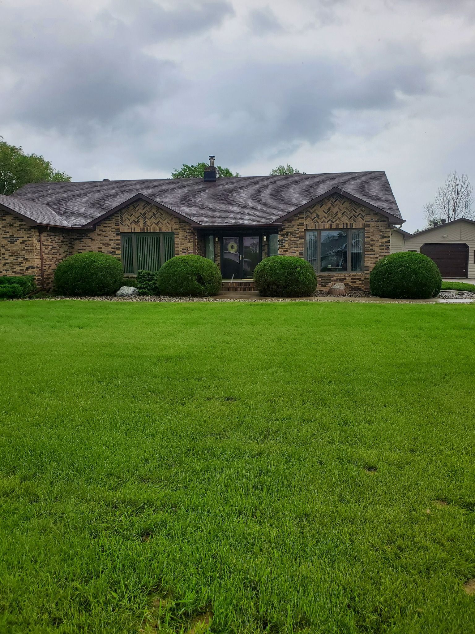A large brick house with a lush green lawn in front of it.