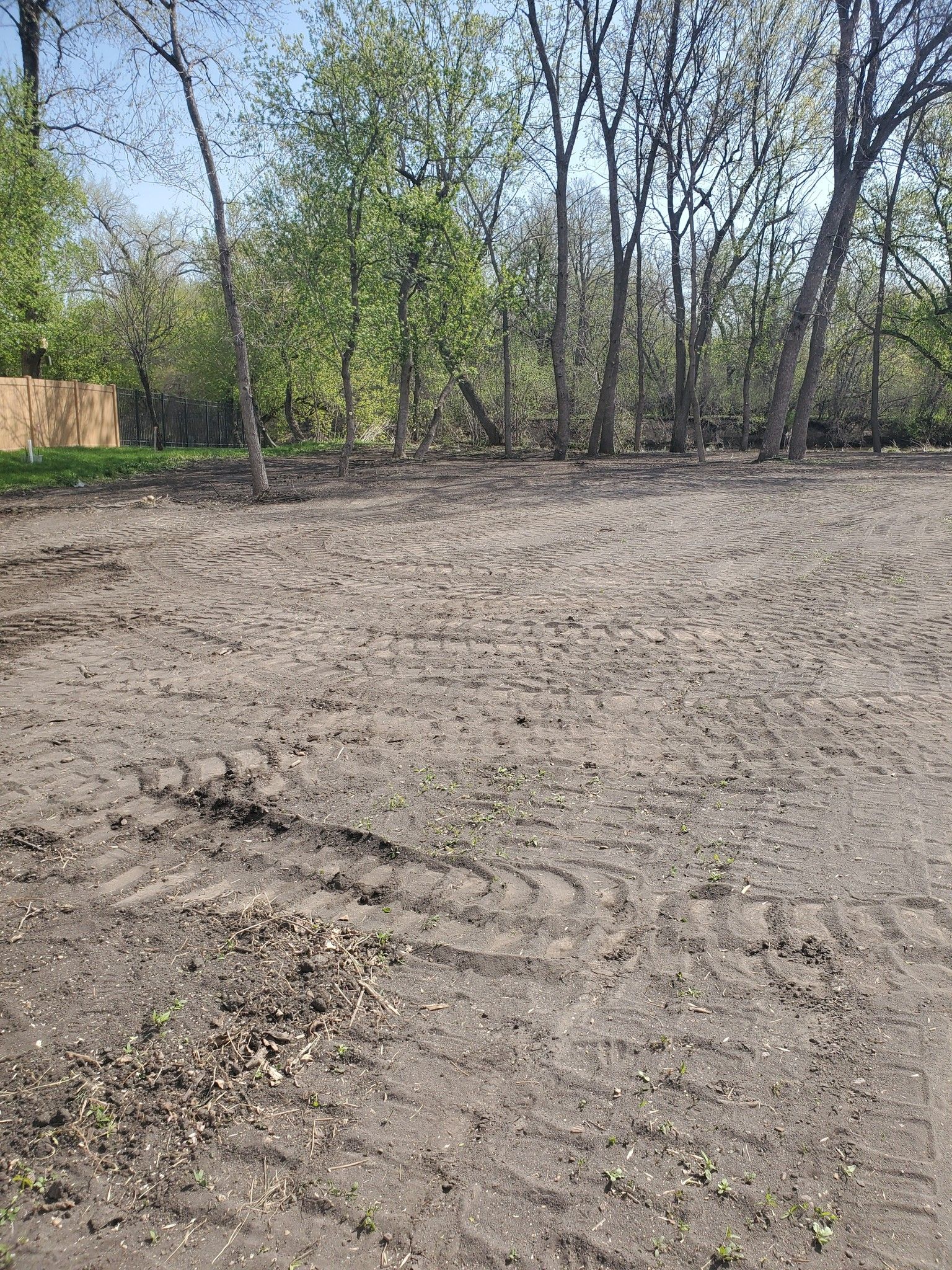 A large dirt field with trees in the background.