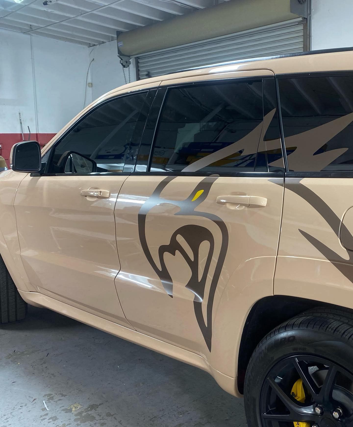 Beige SUV with black decals parked indoors near a garage door
