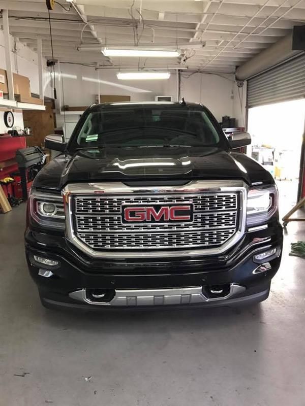 Black GMC pickup truck parked inside a garage, front view