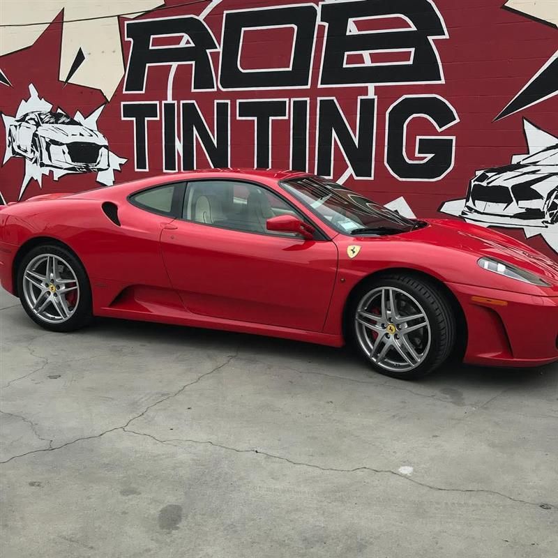 Red sports car parked in front of an ADE Tinting mural wall