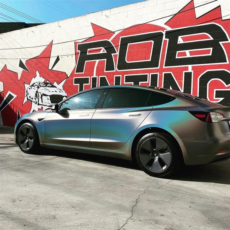 Silver Tesla sedan parked beside a graffiti wall with red and black lettering