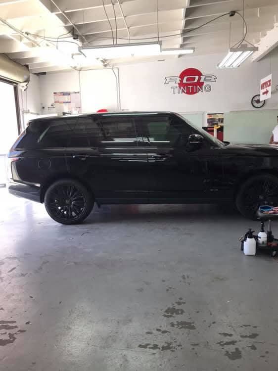 Black SUV parked inside an auto shop garage with white walls and a concrete floor