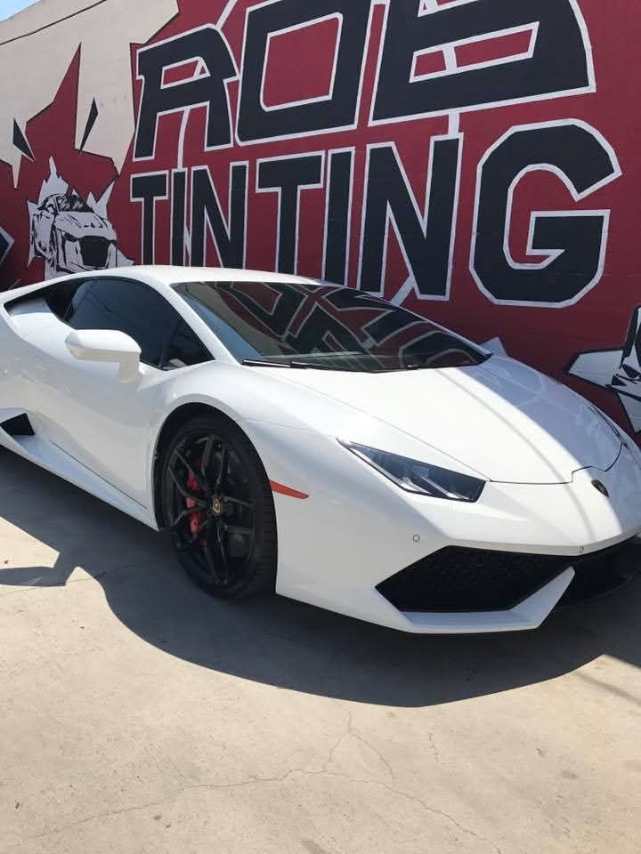White Lamborghini parked in front of a red-and-black “ROD TINTING” wall mural