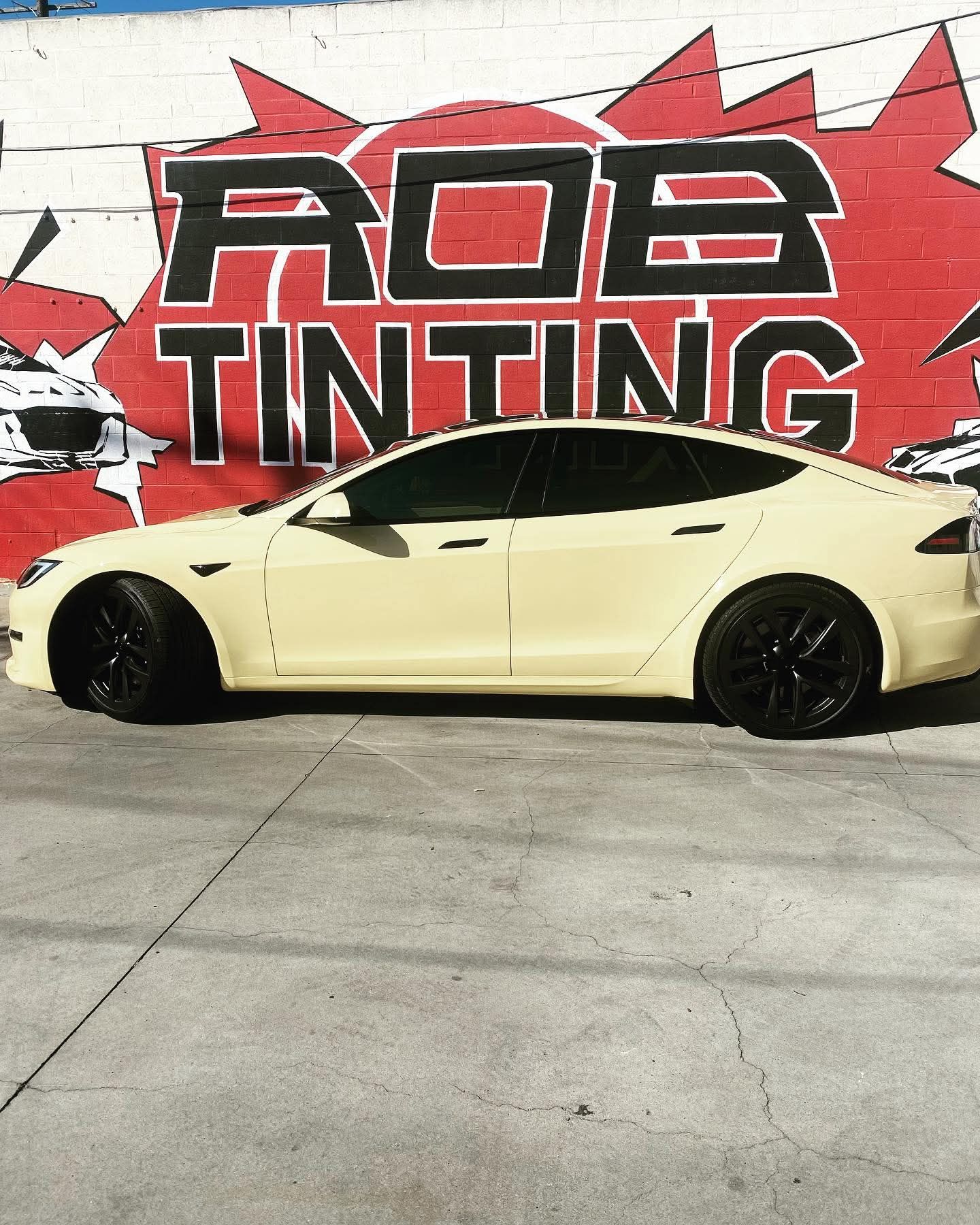 Yellow sports sedan parked in front of an ADB Tinting wall mural