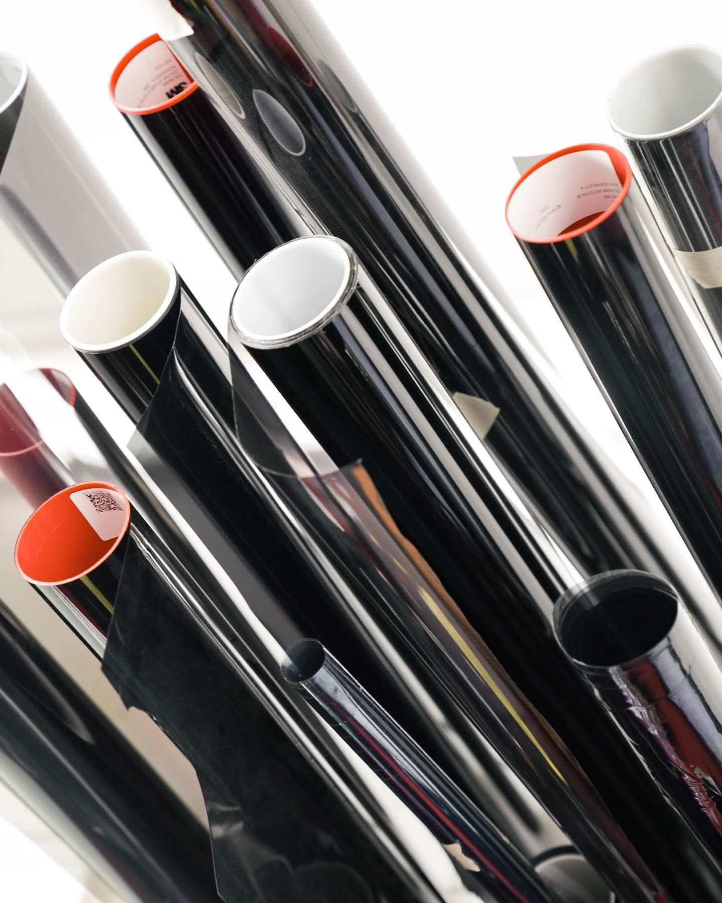 Glossy black metal pipes with white and orange-capped ends stacked diagonally