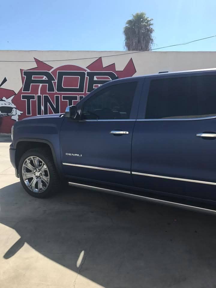 Blue SUV parked outside a tint shop with a large wall sign in the background