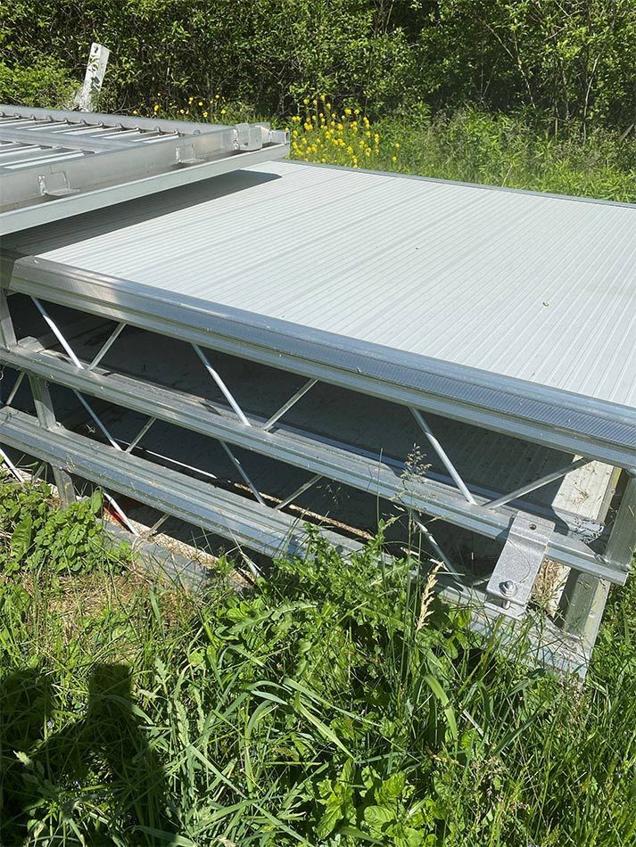 A metal structure is sitting in the middle of a grassy field.