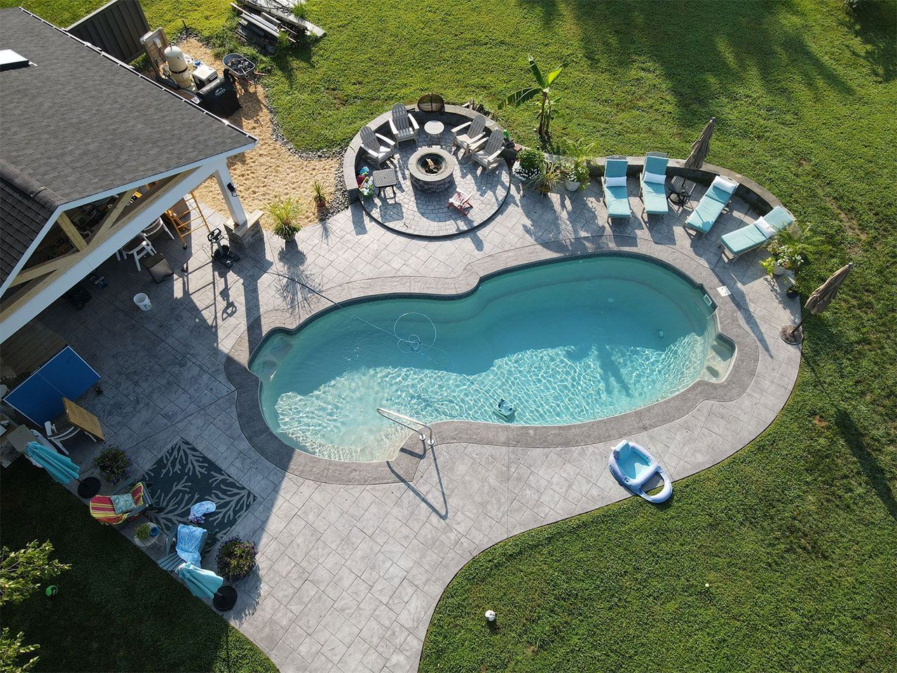 An aerial view of a backyard with a swimming pool and a fire pit