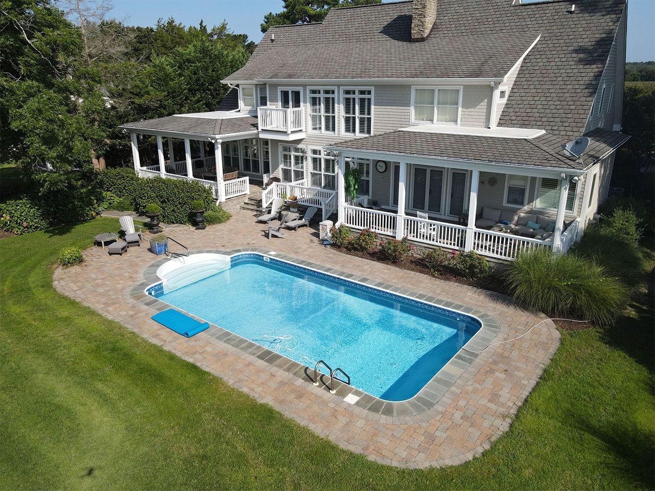 An aerial view of a large house with a large swimming pool in the backyard