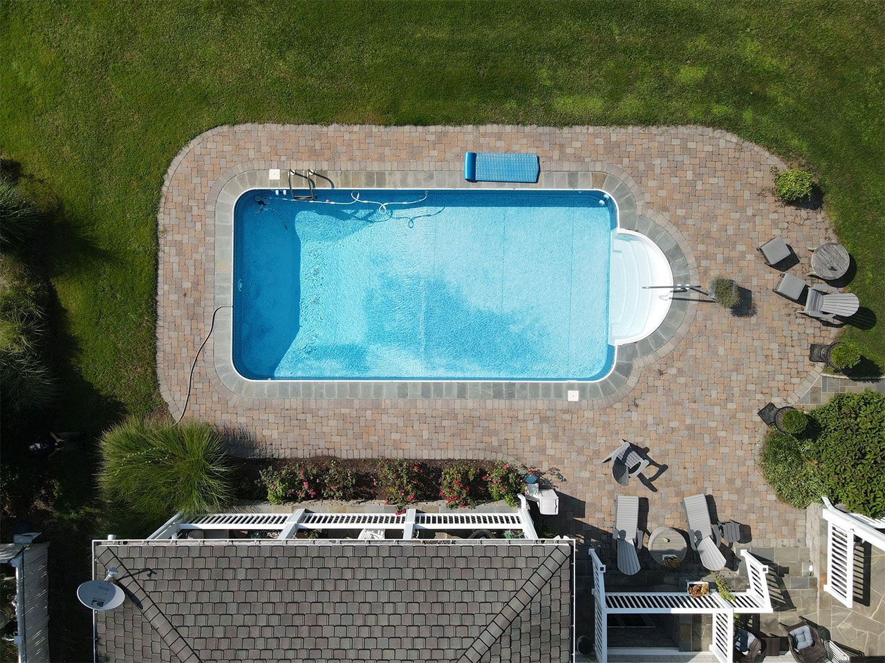 An aerial view of a large swimming pool in the backyard of a house