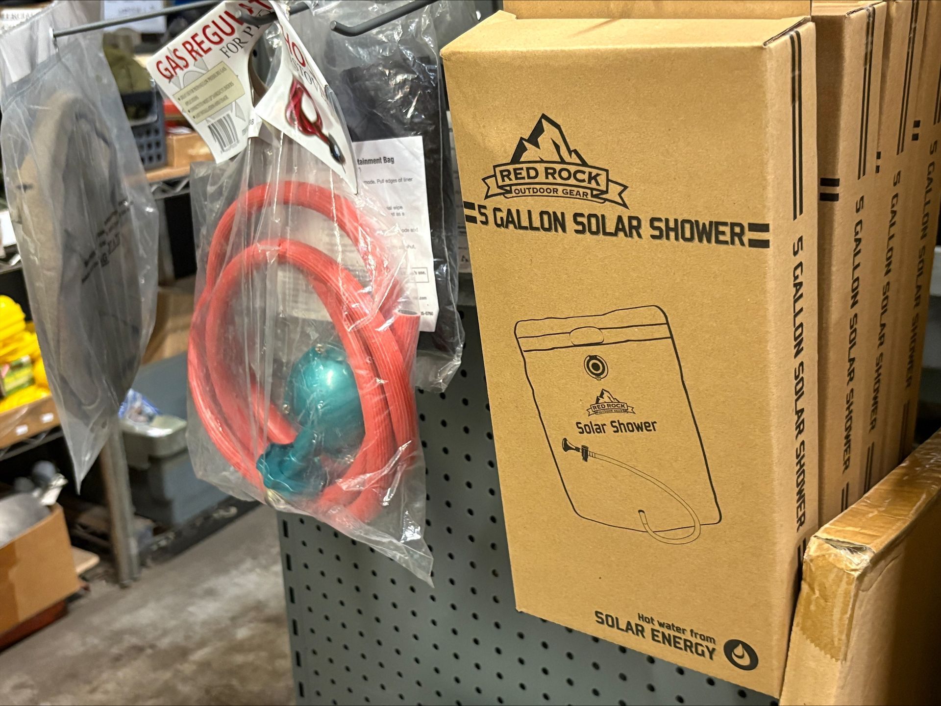 A box labeled 'Blue Ridge 5-gallon solar shower' next to a red hose and a spray nozzle in a store.