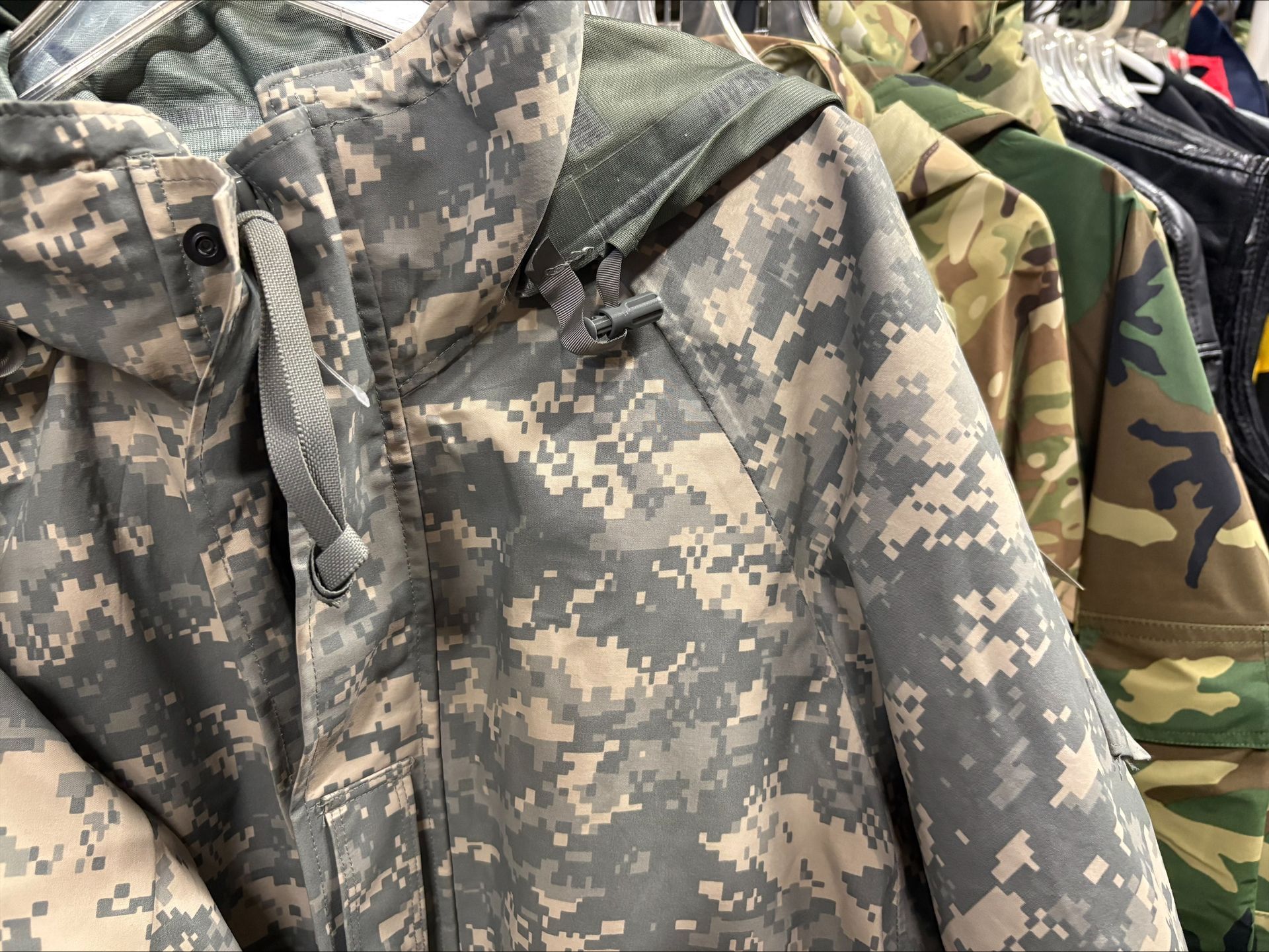 Camouflage jackets on a clothes rack, various colors and patterns.