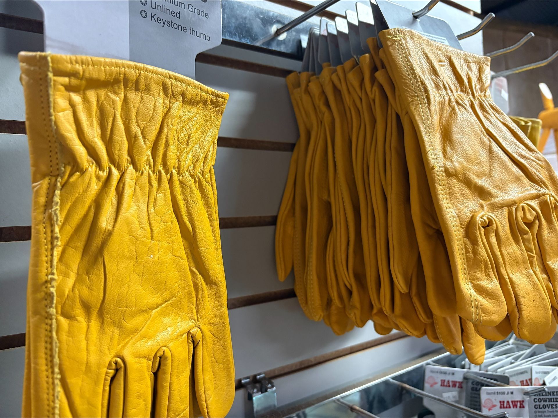 Yellow leather work gloves hanging on display.