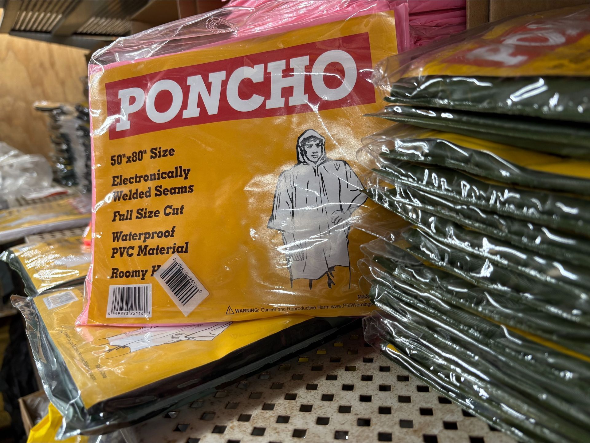 Pile of packaged yellow rain ponchos labeled 'PONCHO' in a warehouse setting.