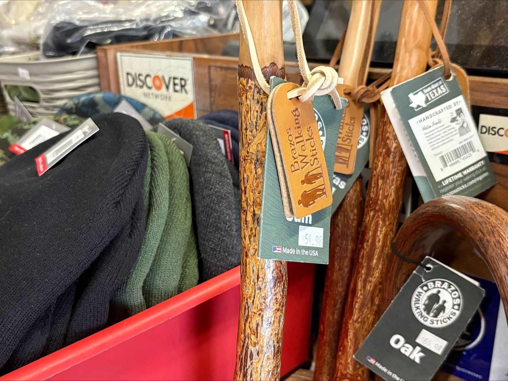 Walking sticks with attached tags, displayed with hats in a retail setting.