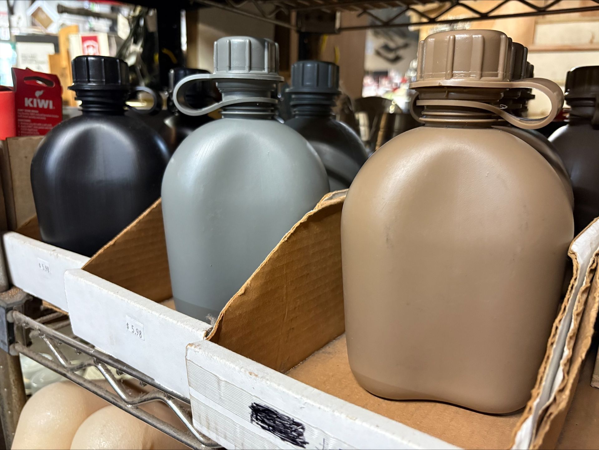 Row of olive green, gray, and black military-style water canteens displayed in a store.