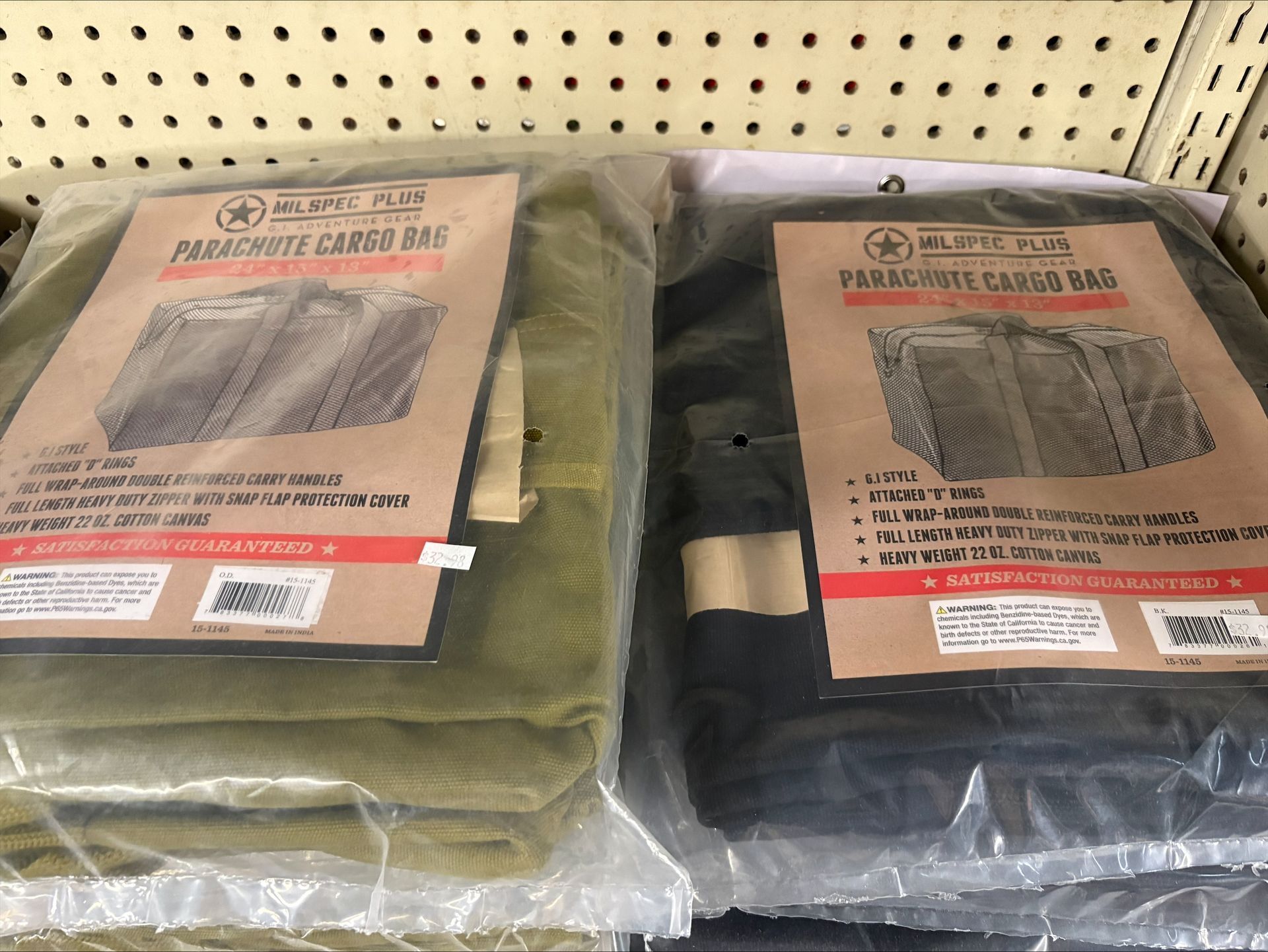Two parachute cargo bags in olive and black, packaged with labels in a store.