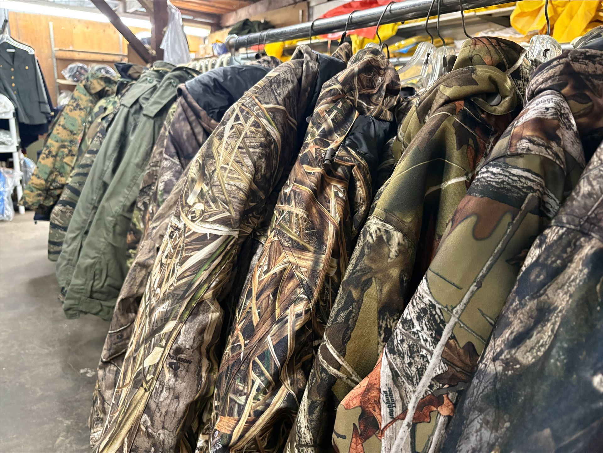 Hunting jackets with camouflage patterns hanging on a metal rack.
