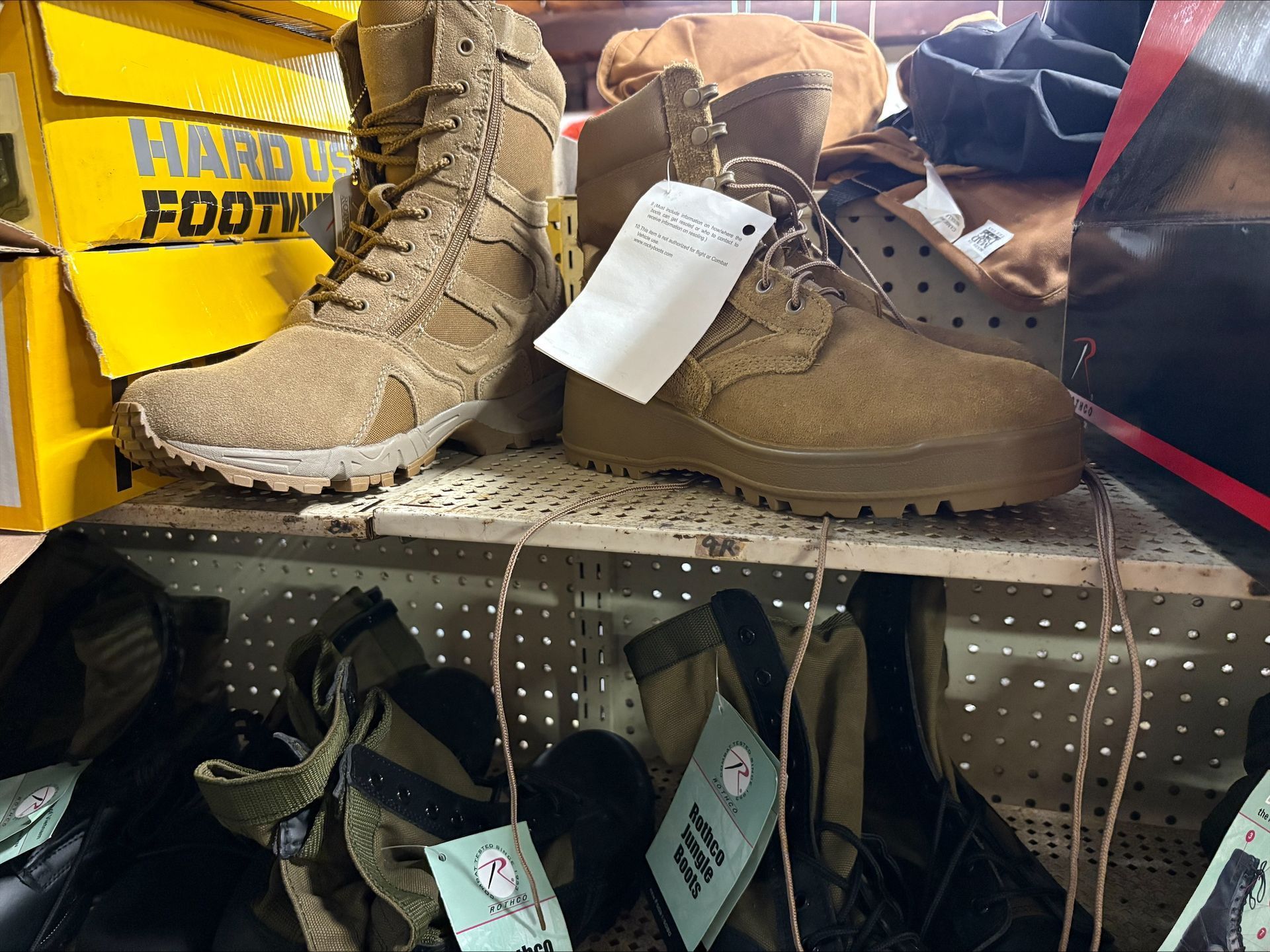 Tan combat boots on a shelf with a price tag, other boots and boxes in the background.