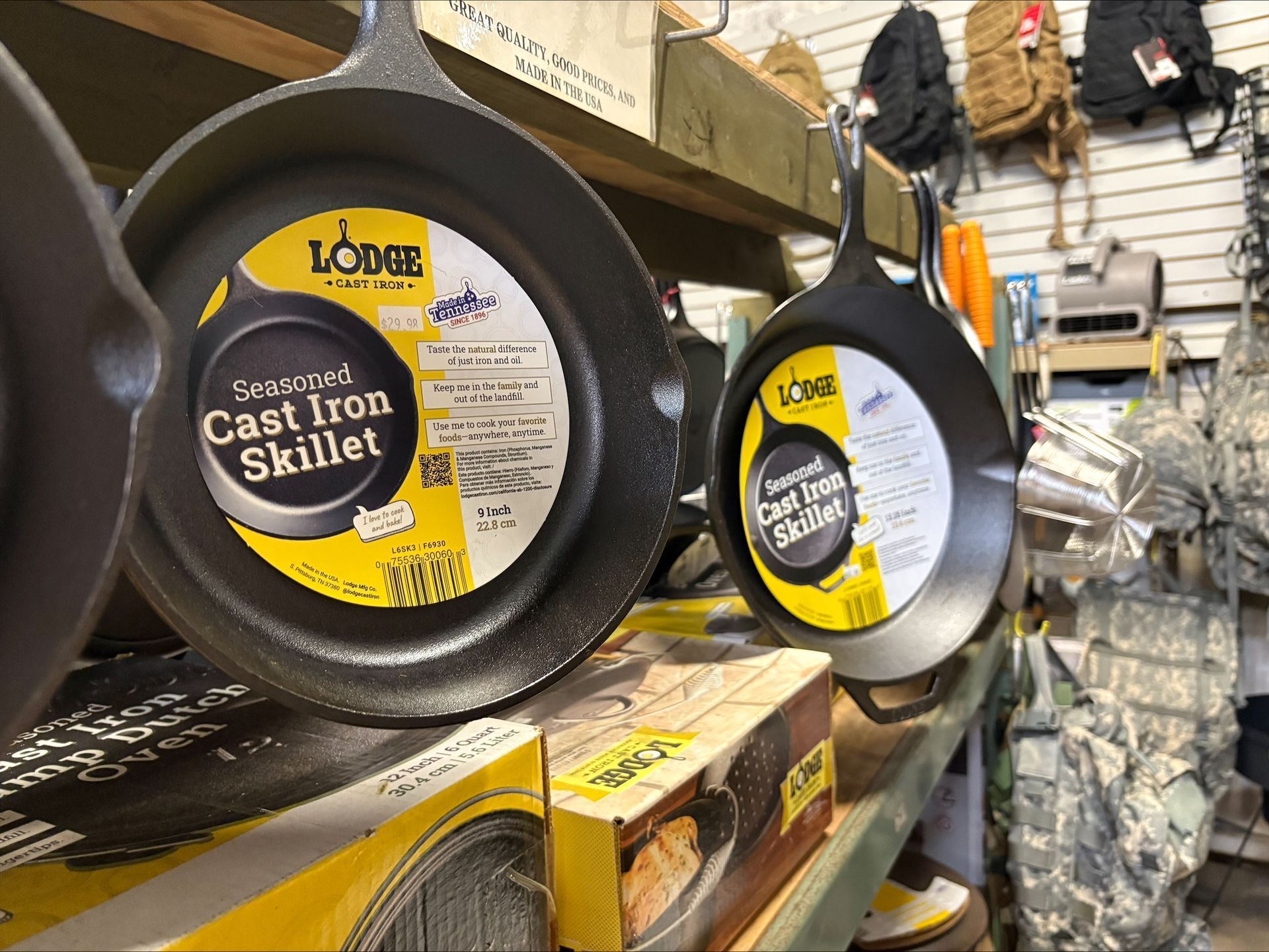 Two Lodge cast iron skillets on a store shelf, with attached yellow labels.