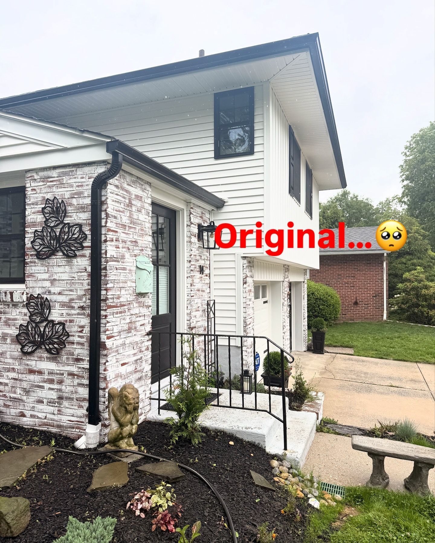 Two-story white house with black trim, brick facade, front porch, and garage. Overcast sky.