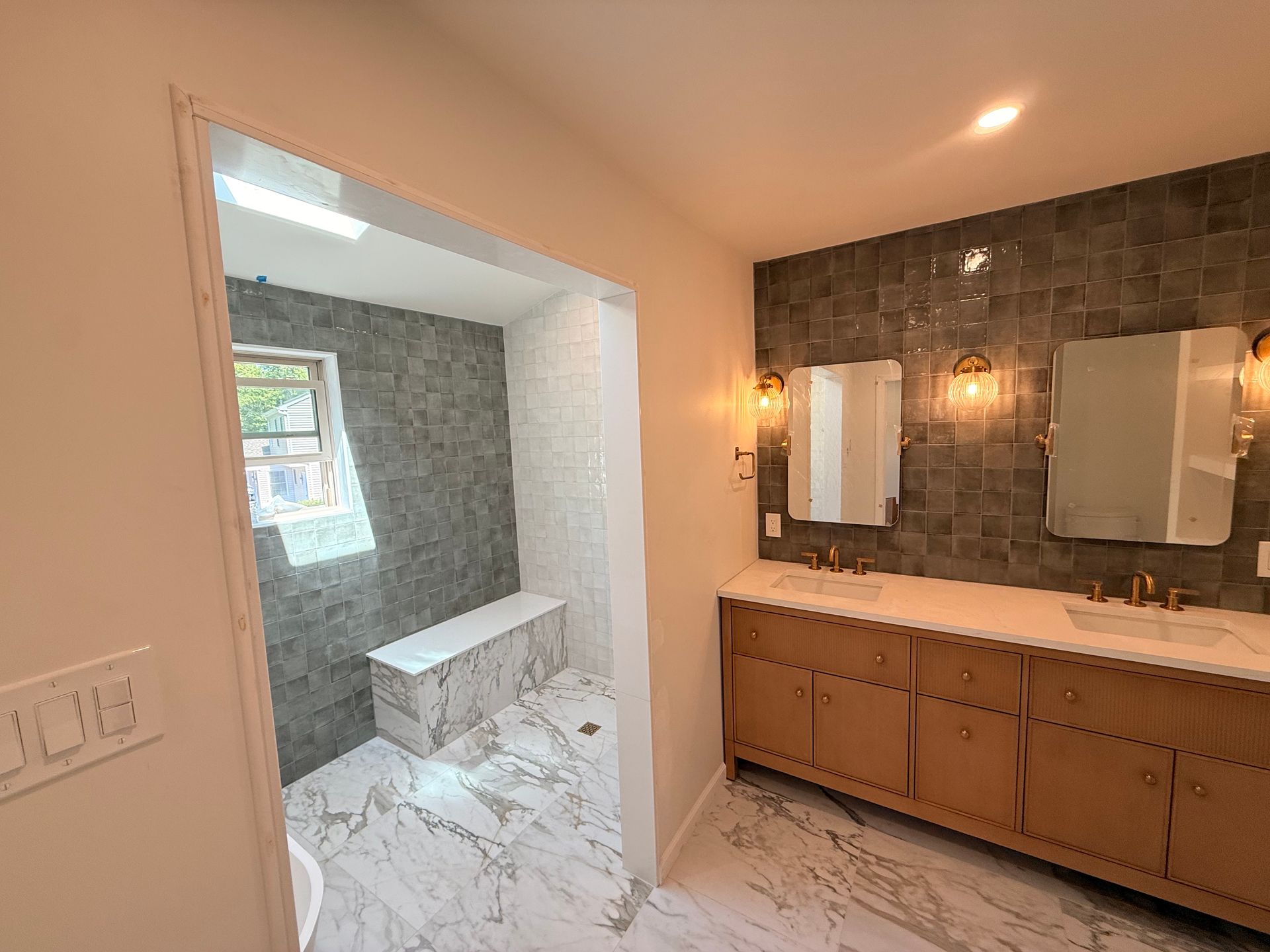 Bathroom with marble floors, tiled shower, double vanity, and sconces.