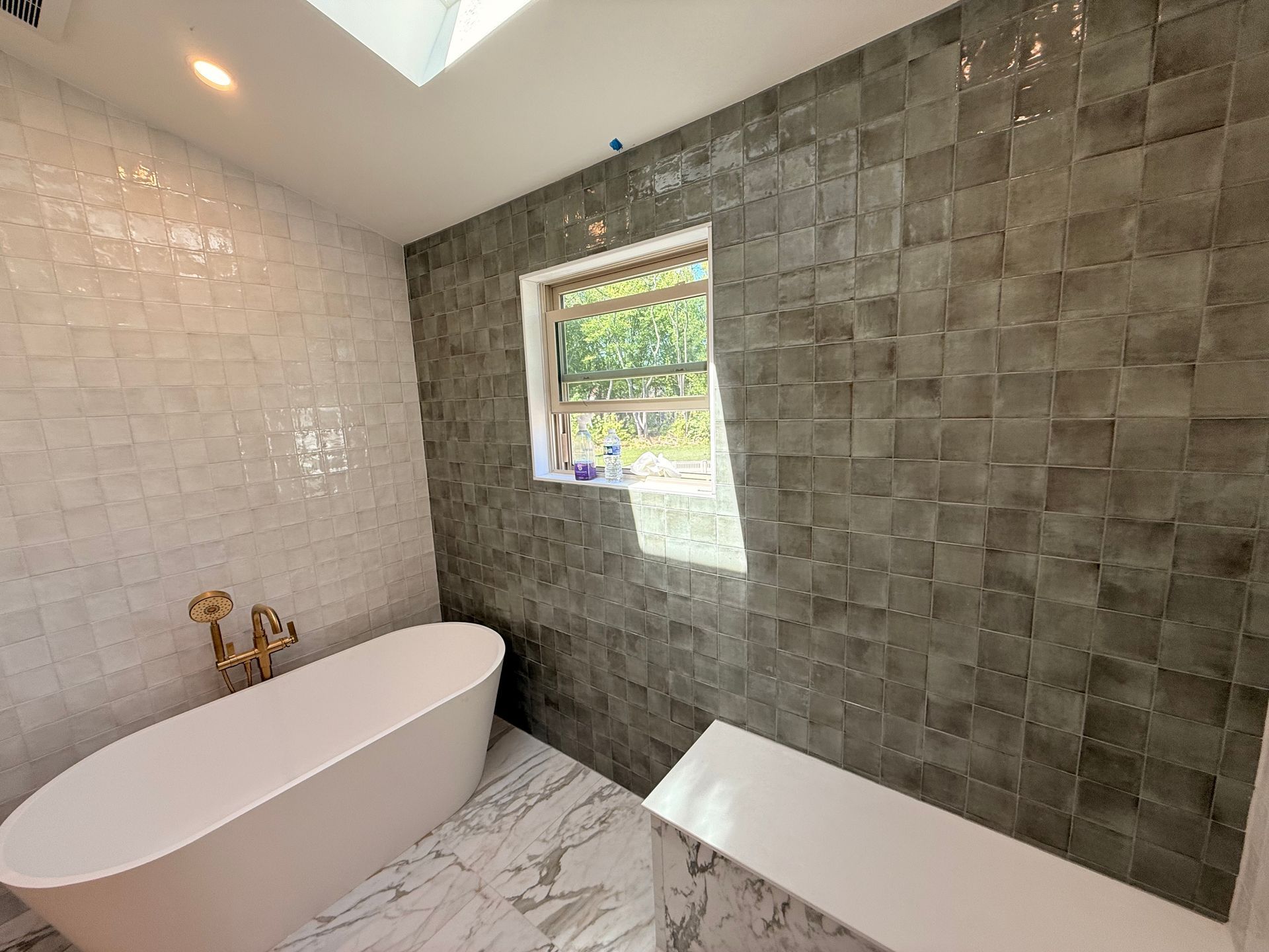 Bathroom with white oval tub, marble floors, and textured gray and white tile walls.