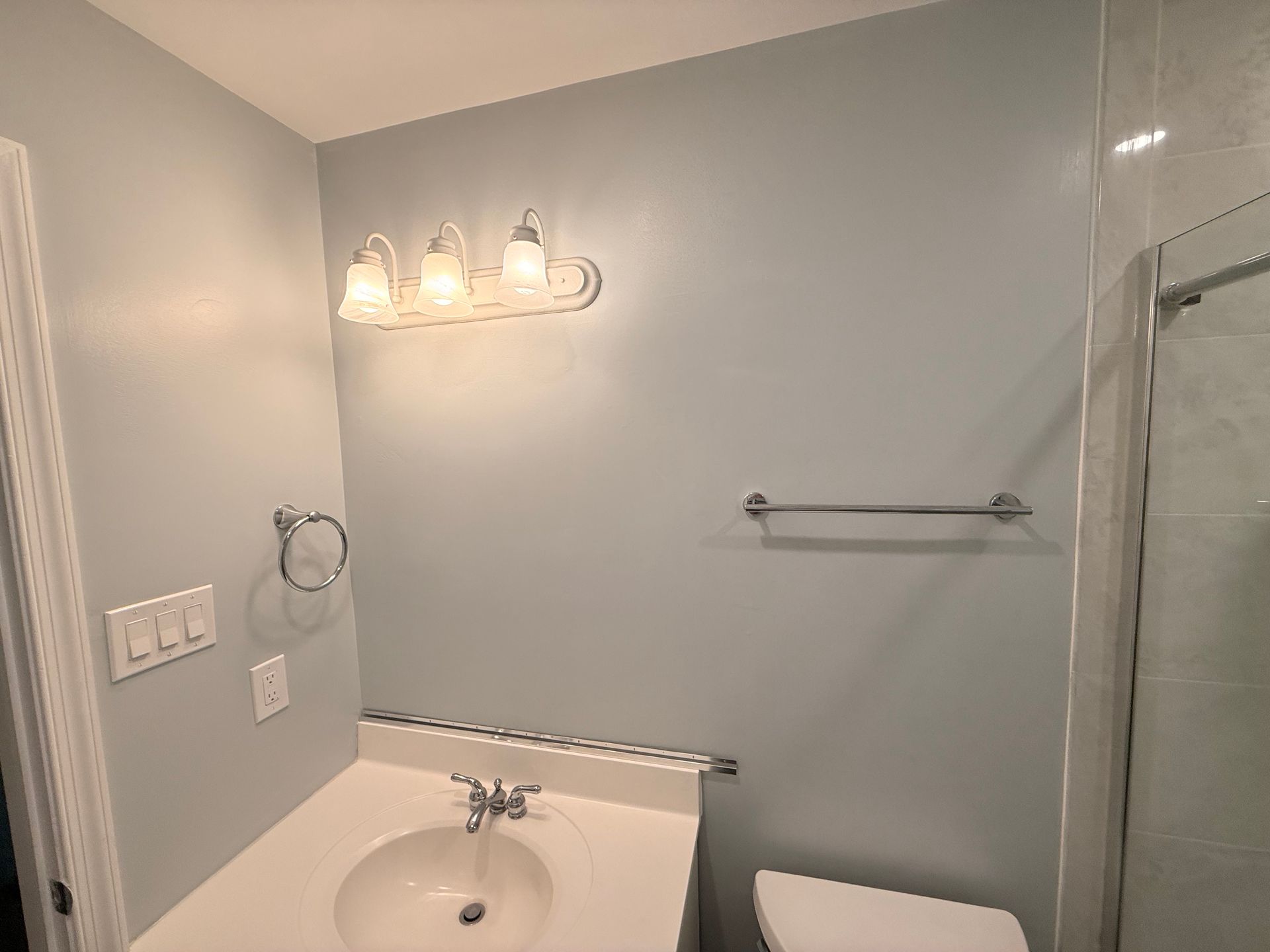 Bathroom with light blue walls, vanity, sink, toilet, and towel rack.