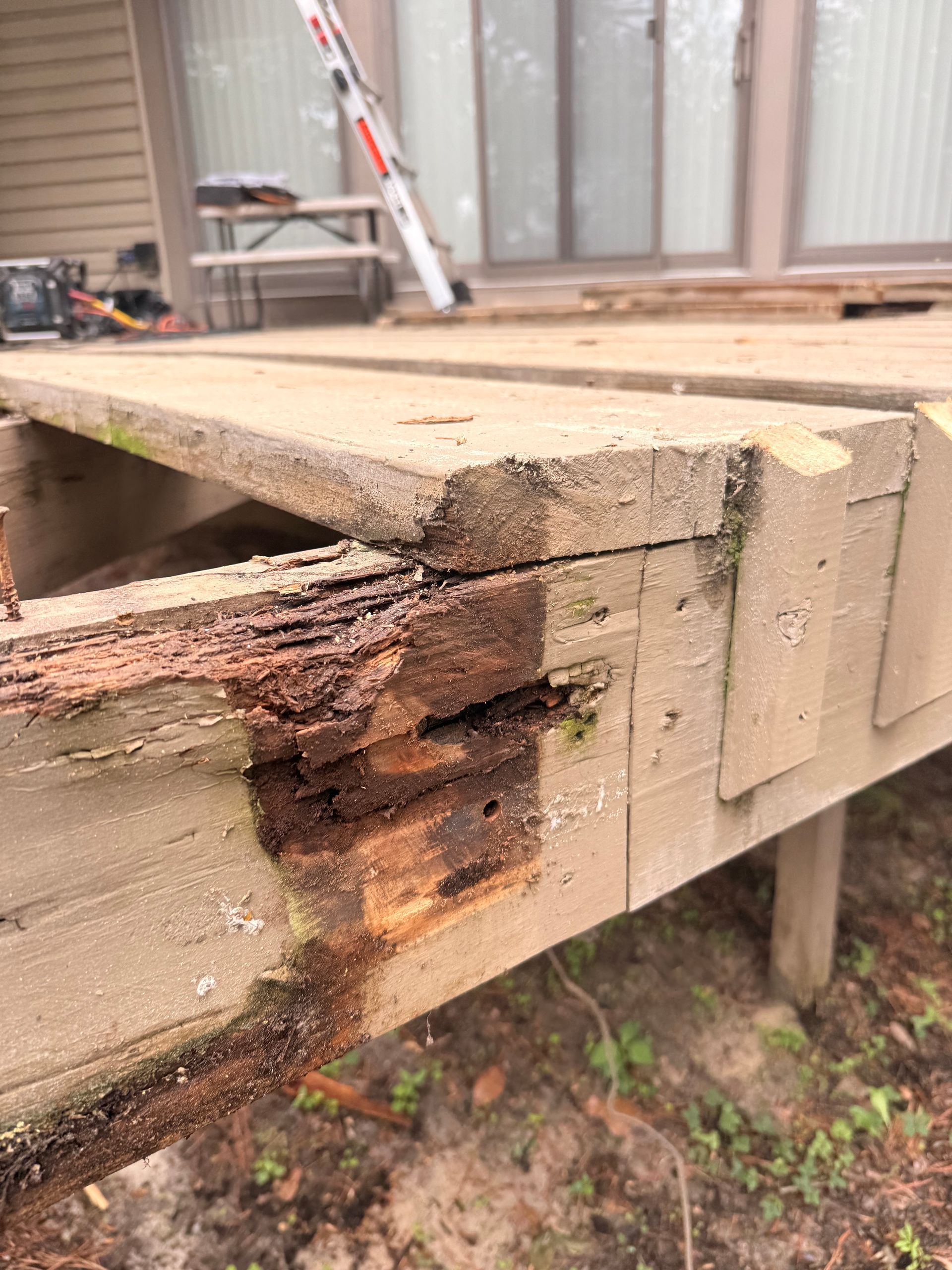 Damaged wooden deck support, showing rot and splintering; exterior setting.