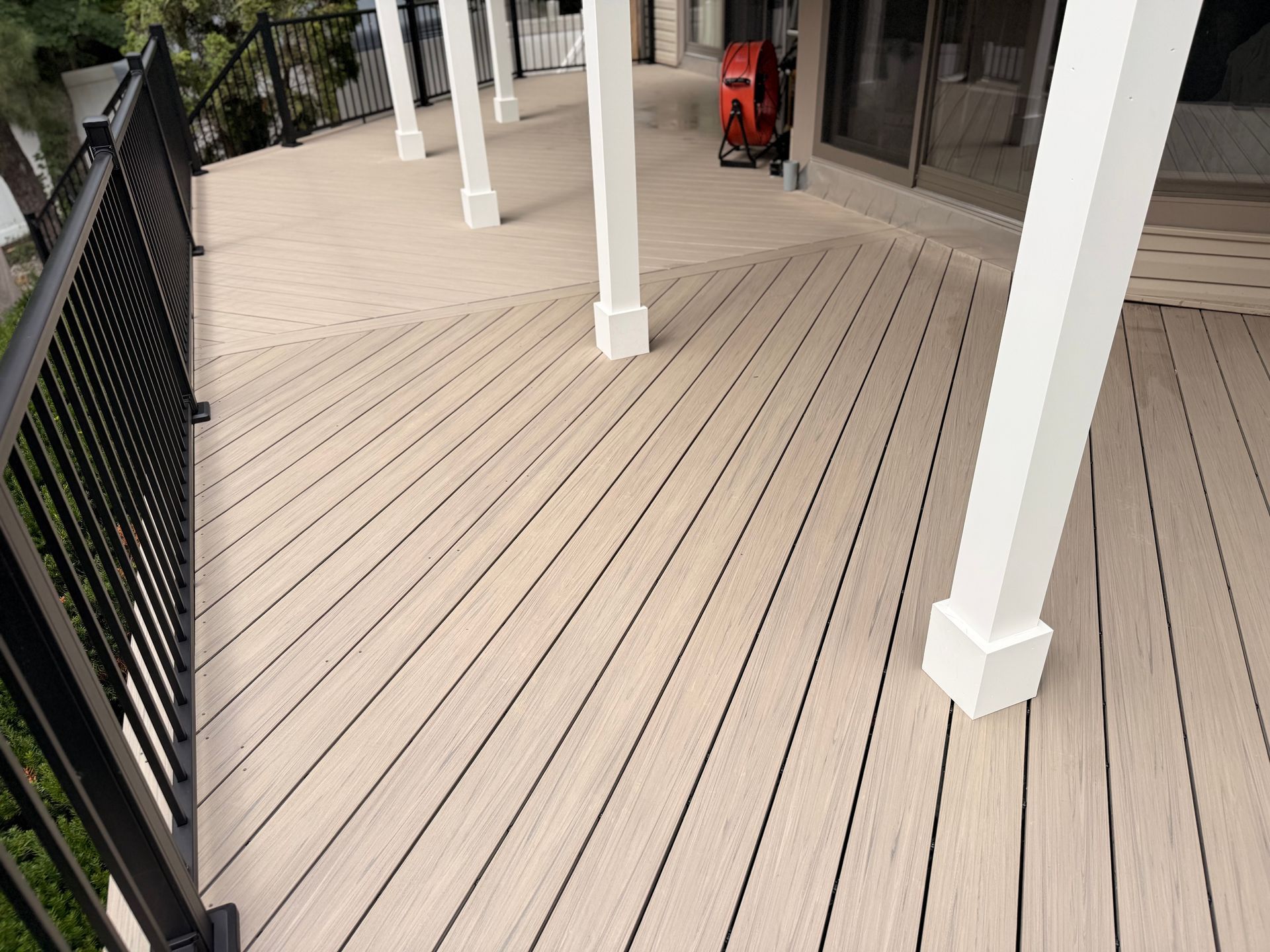 Beige composite deck with black railing and white support columns.