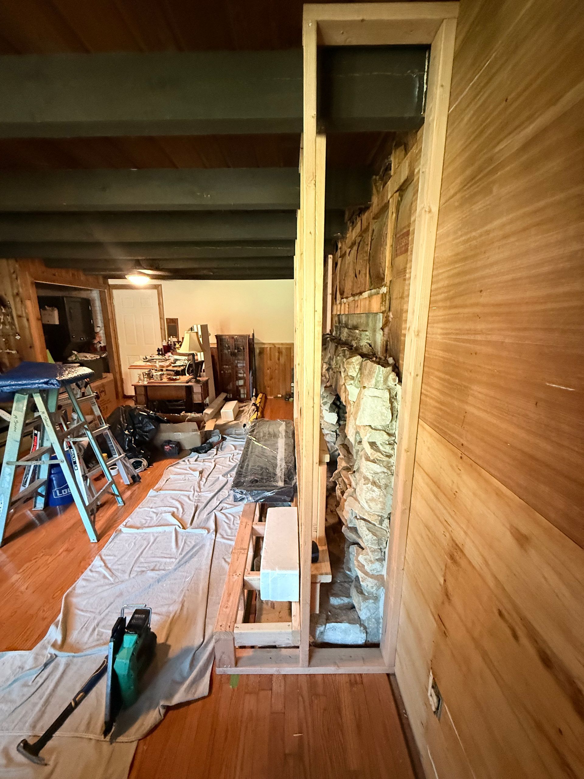 Interior view of a construction project. A wall is being framed around a stone wall.